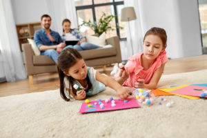 family, leisure and childhood concept - happy sisters doing arts and crafts at home